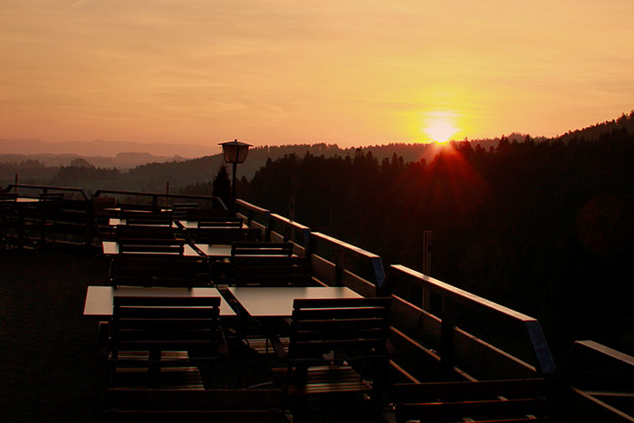 Sonnenuntergang im Hügelland mit Terrasse eines Restaurents und Wald