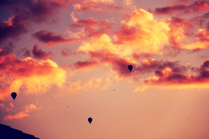 Heissluftballone und Vögel im roten Abendhimmel mit ein paar Wolken