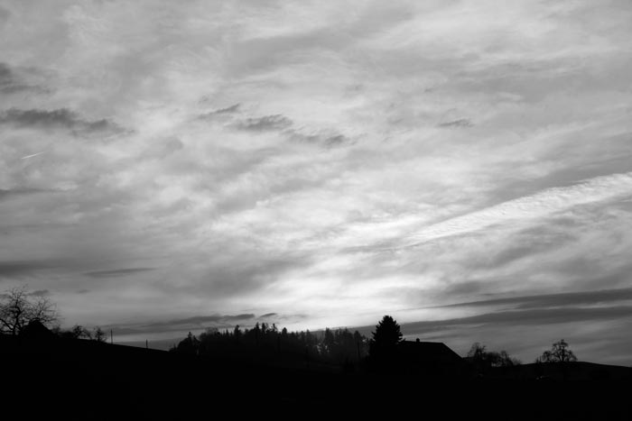 Sonnenuntergang mit und Wolken über Landschaft in schwarzweiss