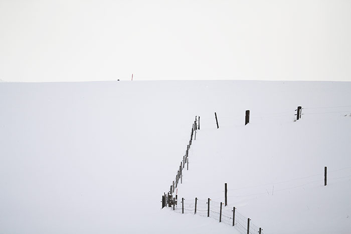 Zaun in verschneitem Hügelfeld