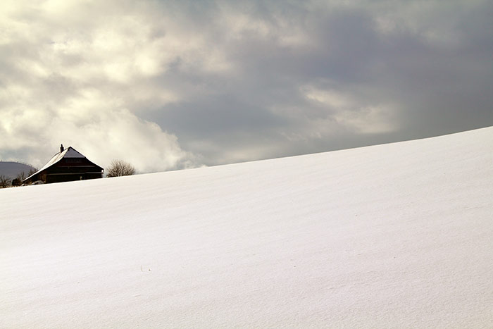 düstere Wolken über Schneelandschaft mit Haus